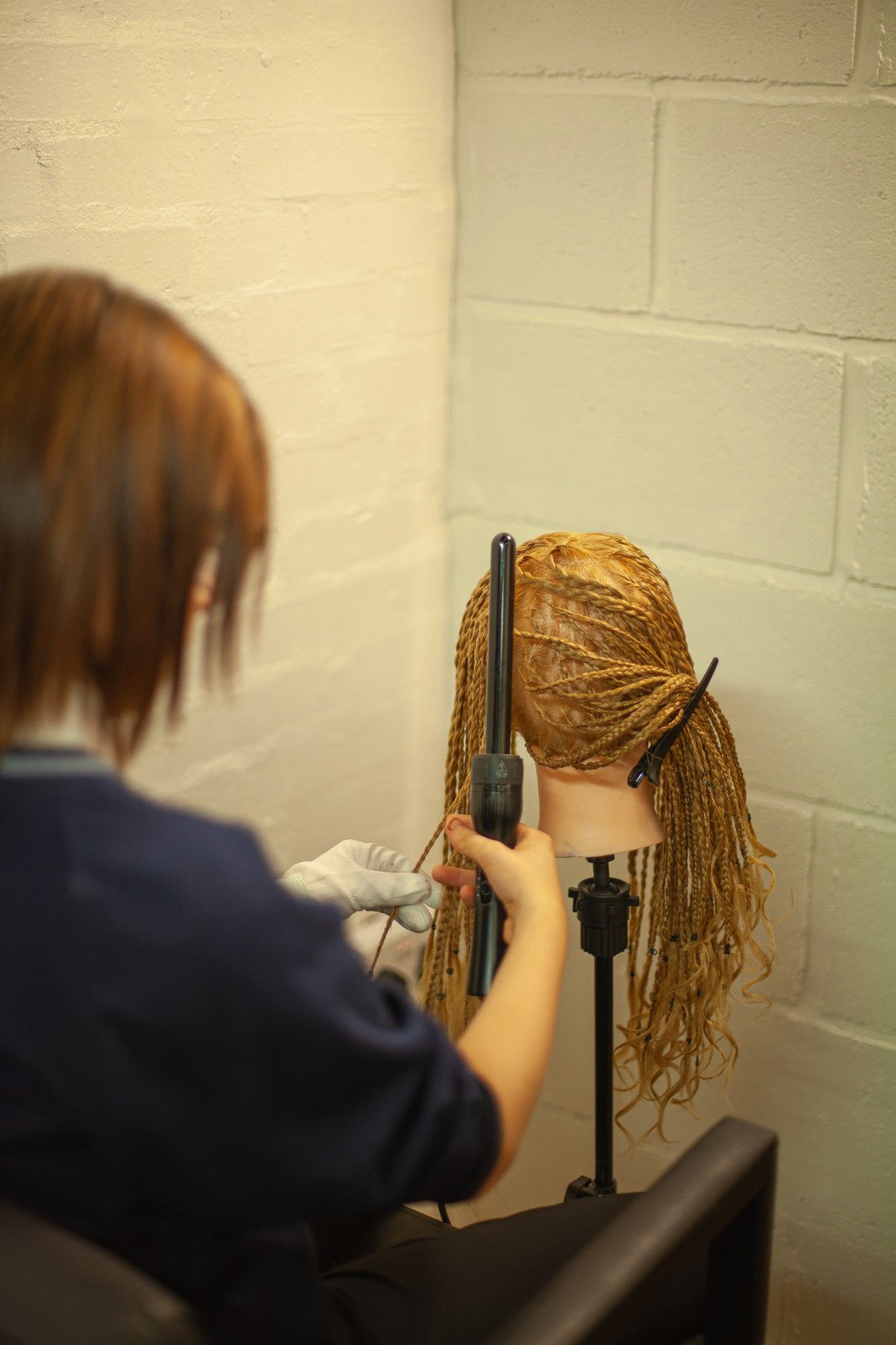A student practising braiding on a training head.